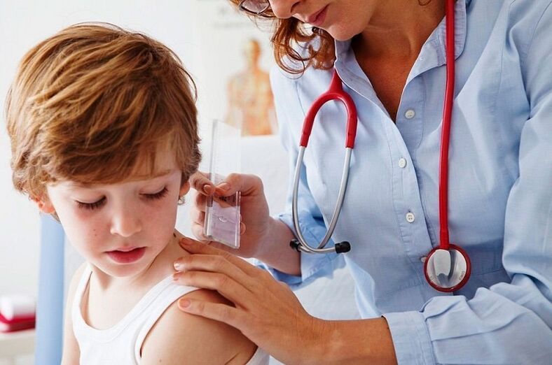 médico examina a un niño con papiloma en el cuerpo